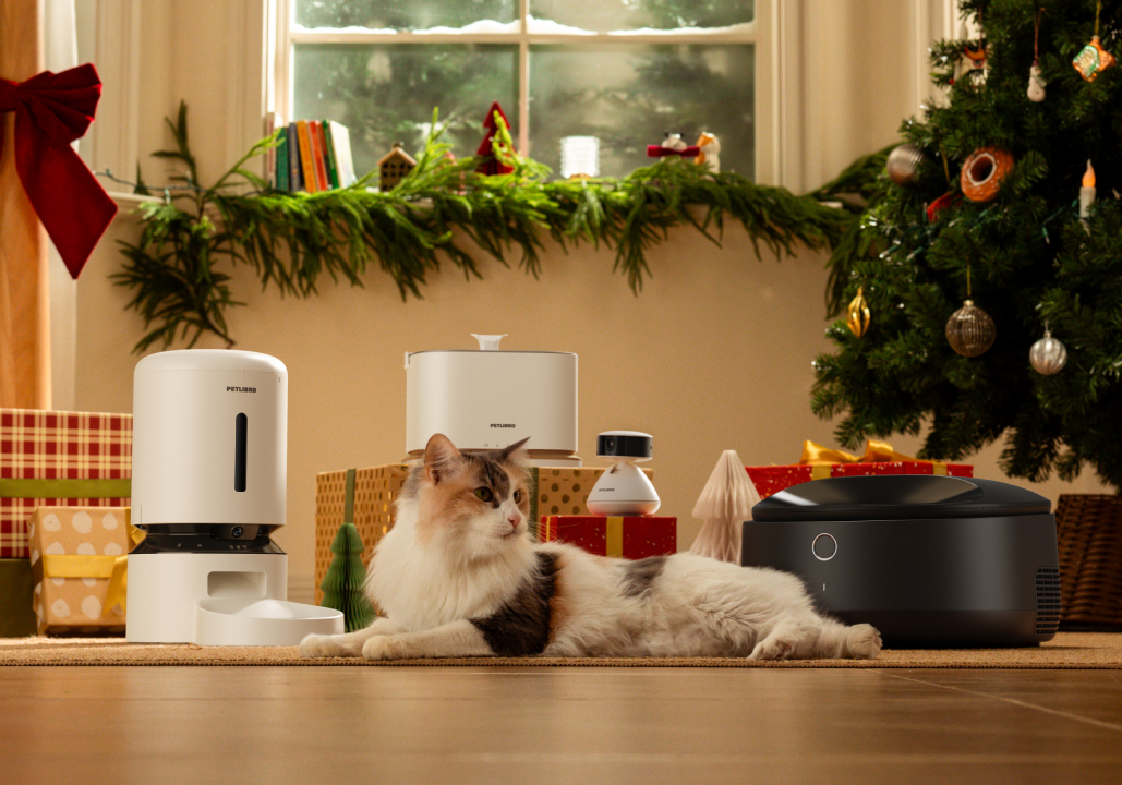 Petlibro PETLIBRO: chat animal de compagnie près d’un distributeur automatique de nourriture, fontaine à eau et bac à litière, décor Noël.